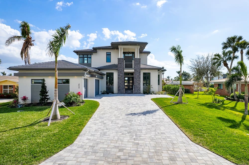 A large white house with palm trees in the front yard.