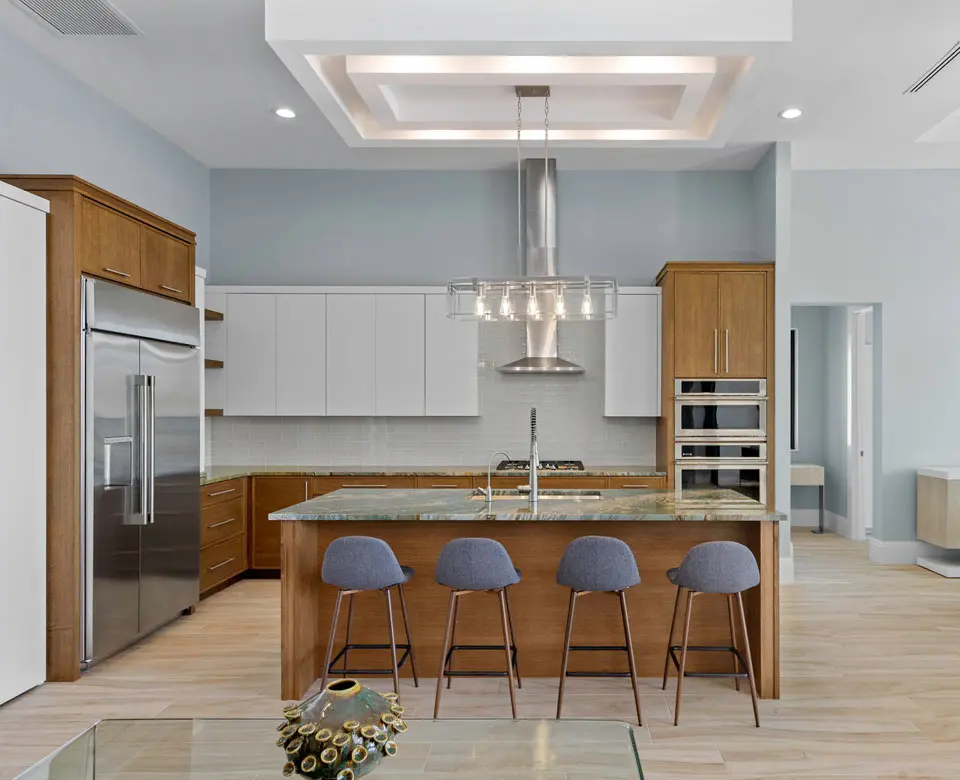 A kitchen with a large island and blue chairs.